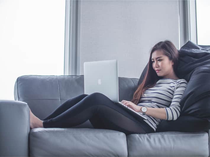 Kvinne som bruker en bærbar datamaskin på sofaen